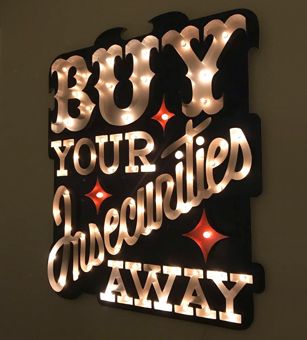 Illuminated sign sculpture: Buy Your Insecurities Away